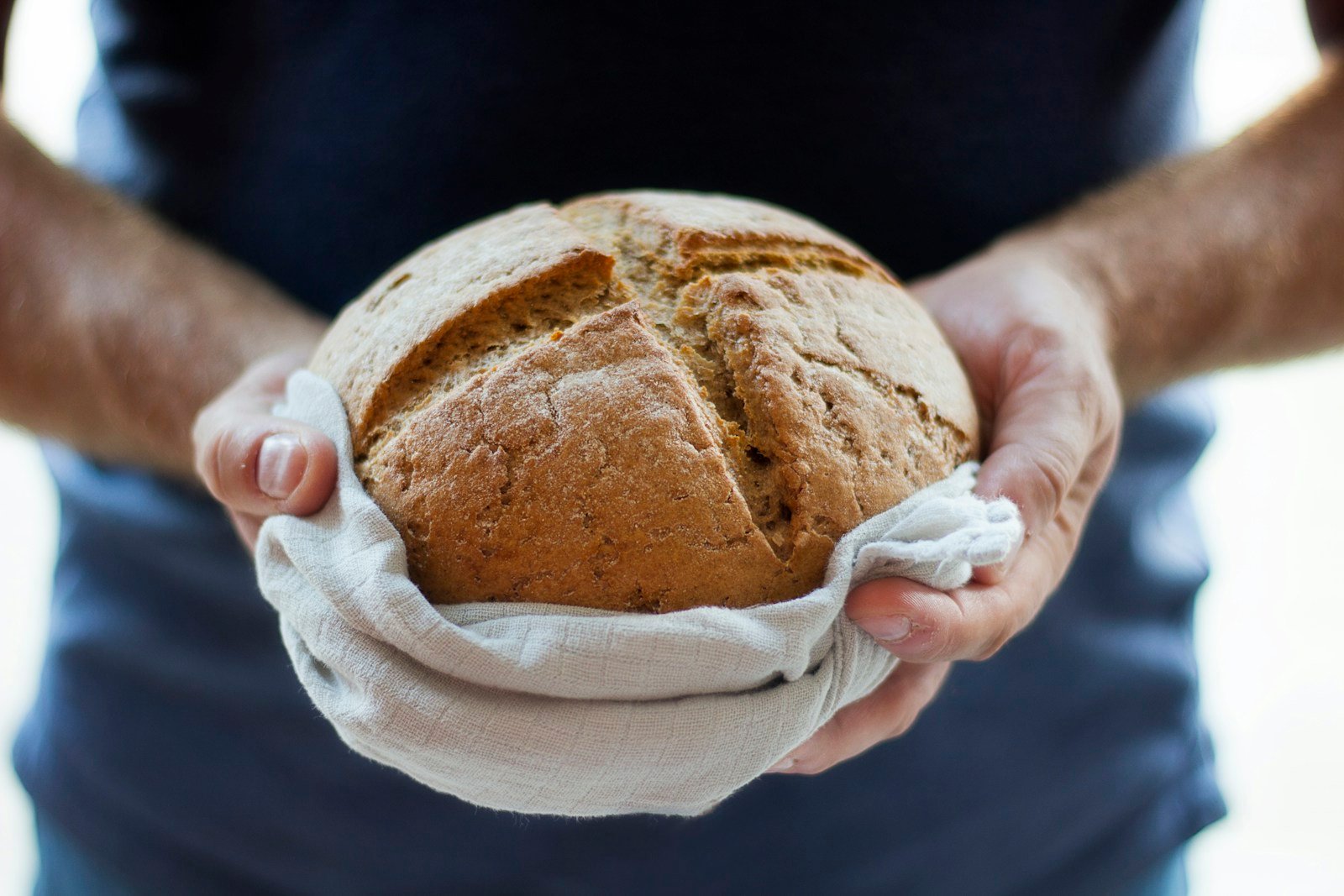 Boulanger tenant une miche au levain derrière son comptoir