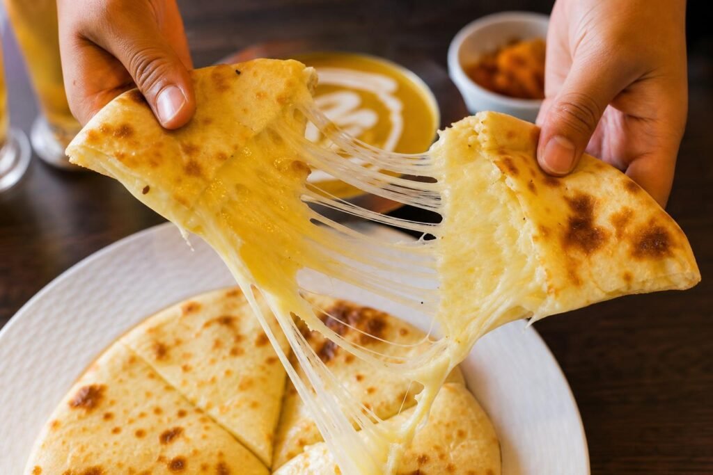 Cheese naan doré ouvert en deux, le fromage fondu qui file