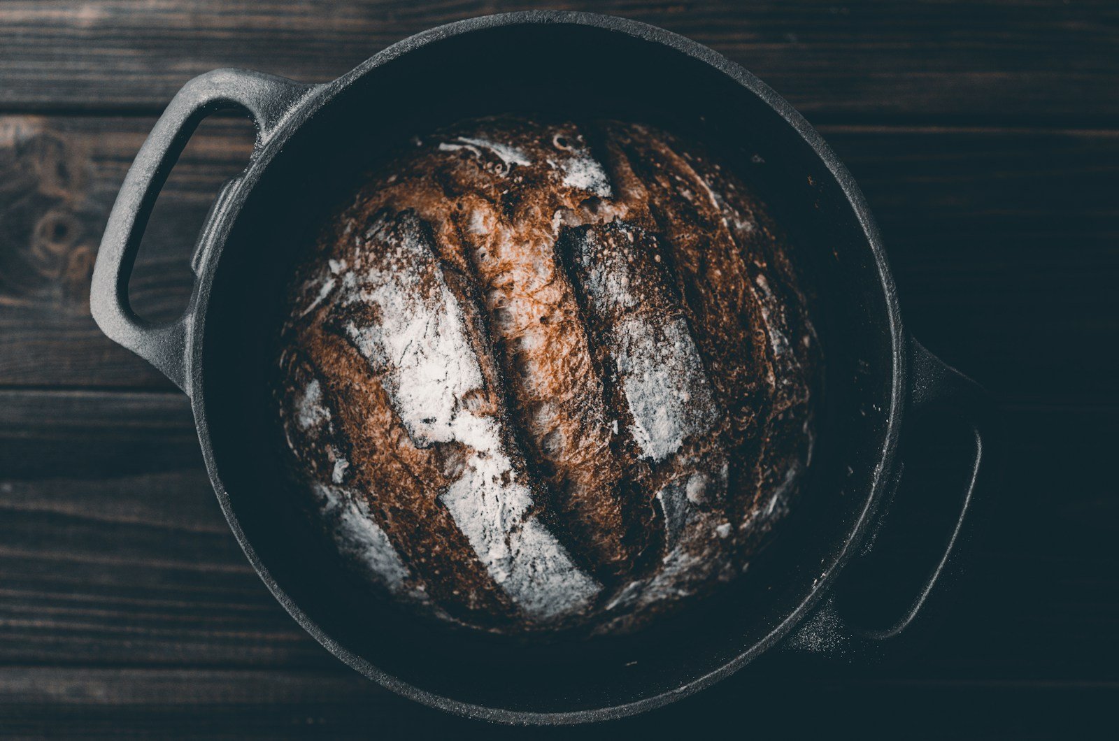 Cocotte en fonte avec couvercle entrouvert sur un pain doré