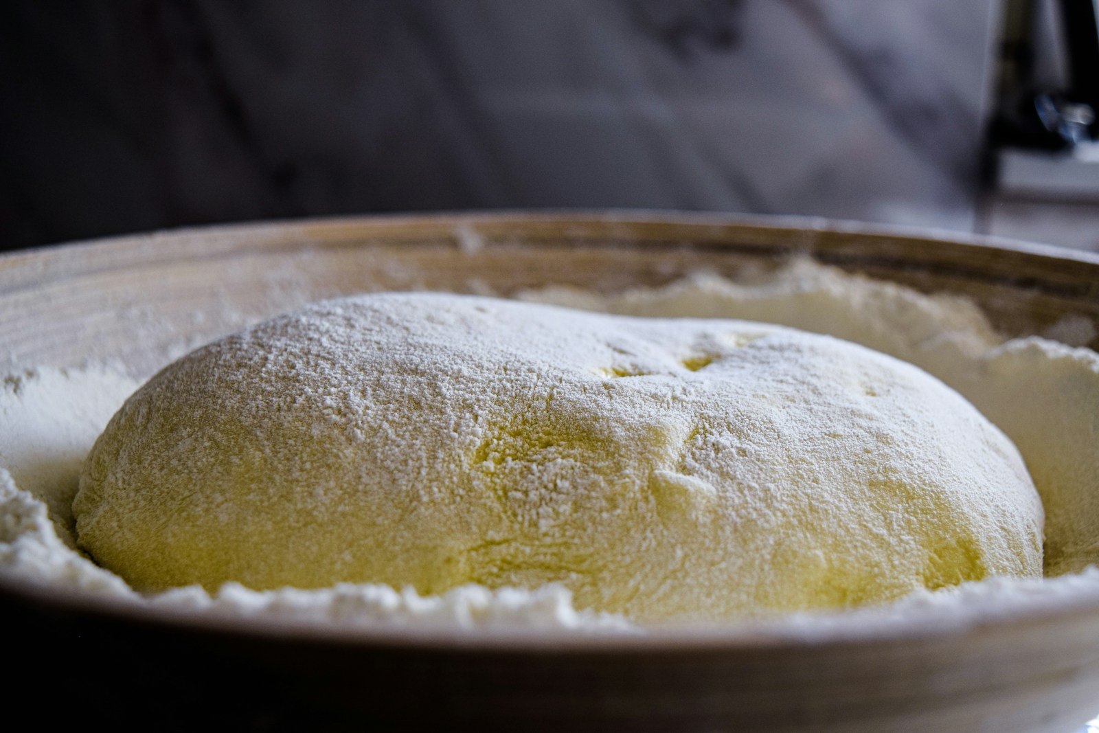 Pâton de pain au levain en pousse dans un banneton d'osier fariné