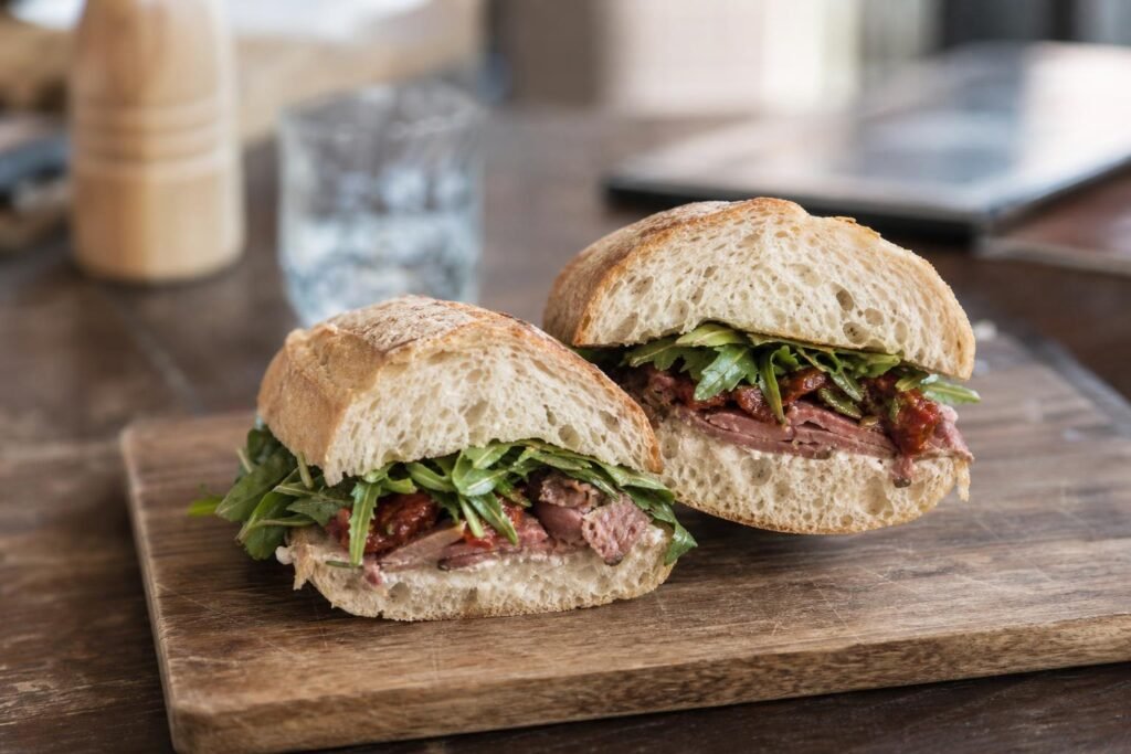 Sandwich sur baguette tranché en deux, posé sur une planche en bois