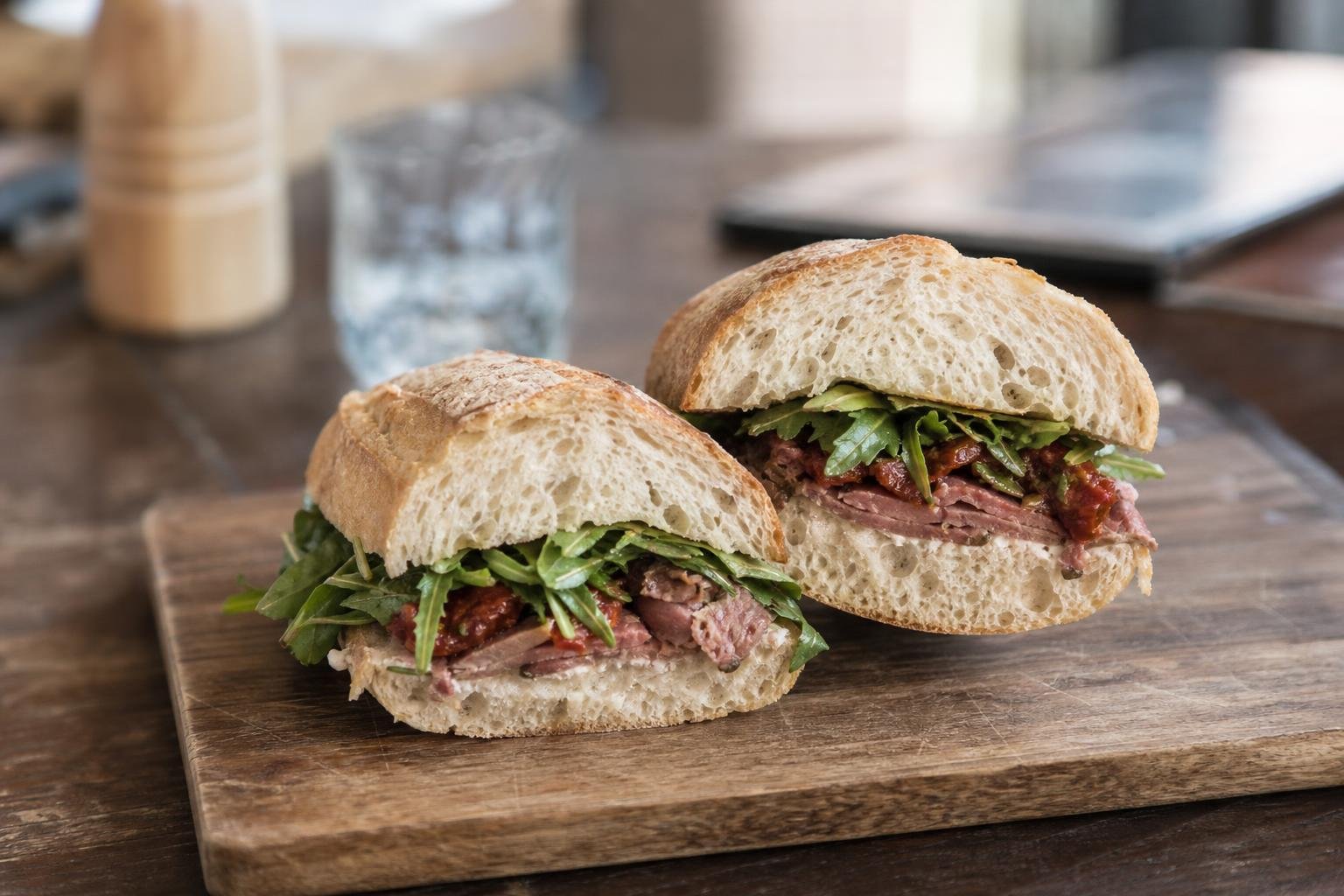 Sandwich sur baguette tranché en deux, posé sur une planche en bois
