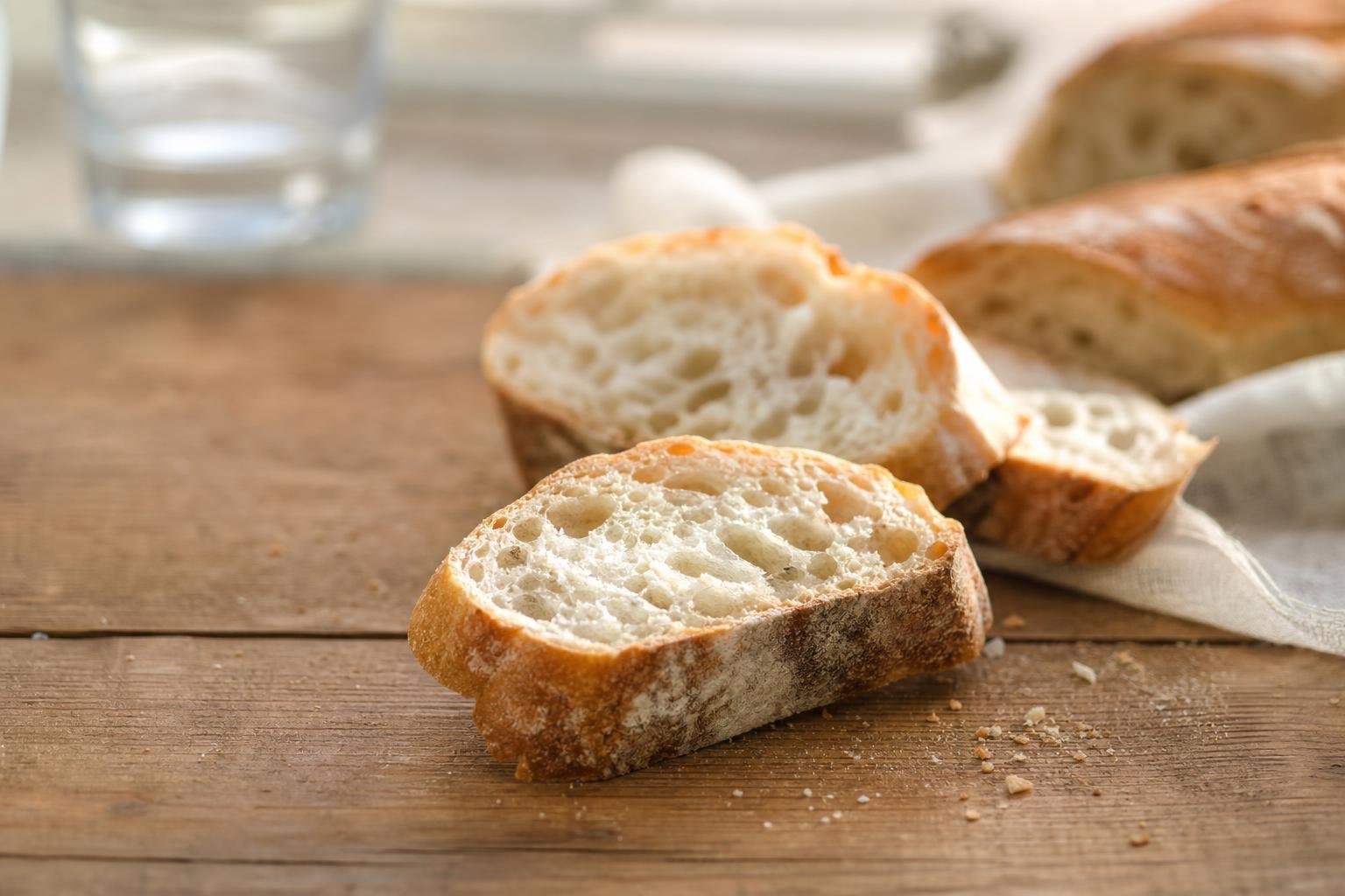 Tranches de baguette de pain français posées sur une table en bois