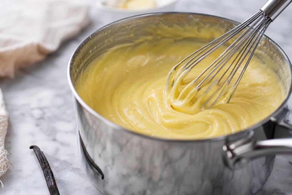 Crème pâtissière à la vanille lissée au fouet dans une casserole