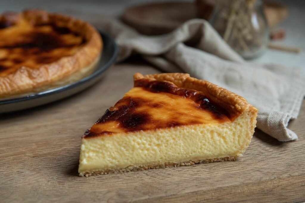 Part de flan pâtissier à la surface caramélisée, posée sur une planche